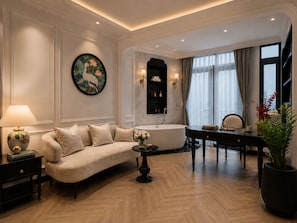Sala de estar bem iluminada com sofá, mesa redonda com vaso, banheira e área de jantar com cadeira e mesa.