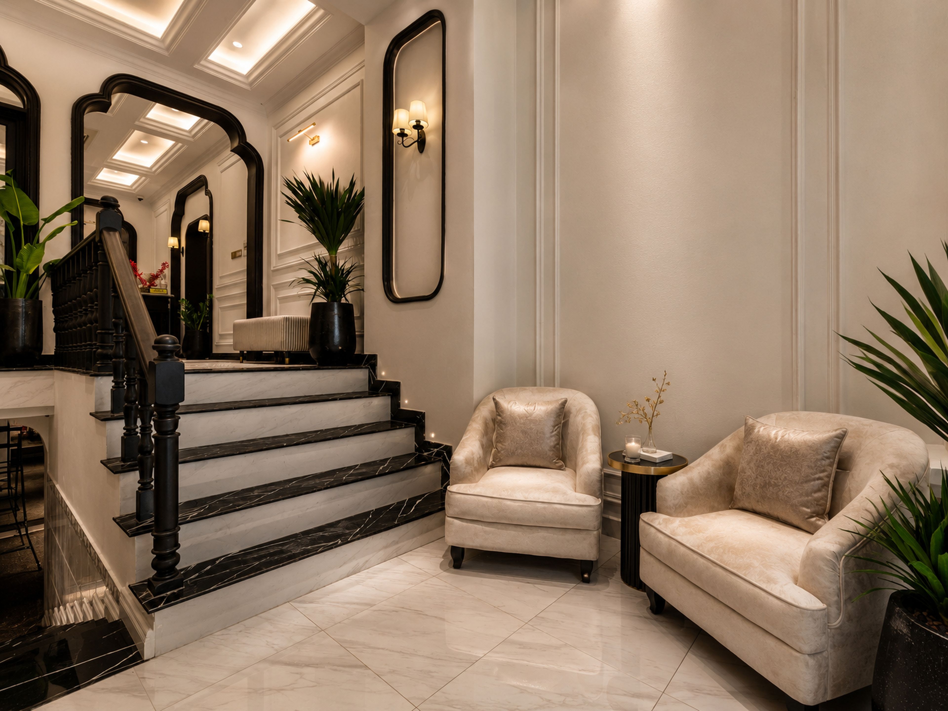 Uma imponente escadaria com acabamento em mármore leva a um espaço de estar com duas poltronas confortáveis e uma pequena mesa, tudo cercado por plantas em vasos e um espelho grande.