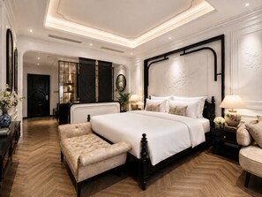 Een ruime slaapkamer met een groot bed, een zithoek en een aparte badkamer.