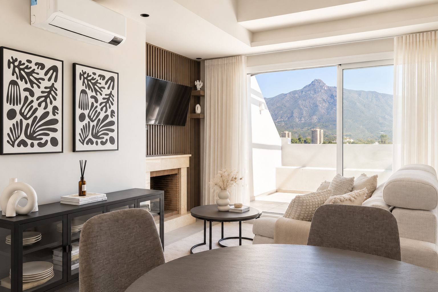 Uma sala de estar moderna com lareira, televisão de tela plana e varanda com vista para as montanhas.