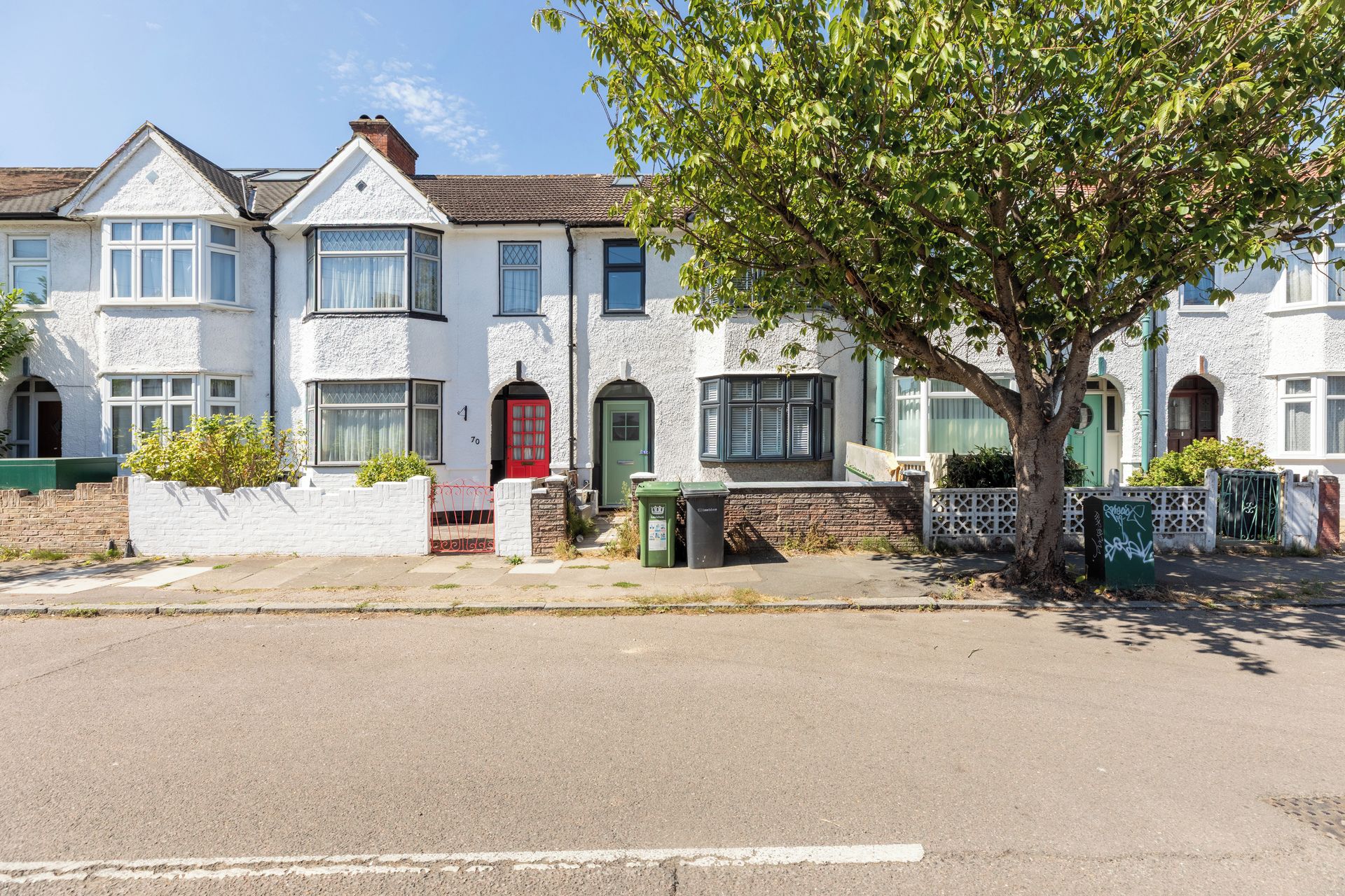 A row of white terraced houses with a tree in front.