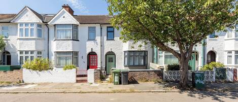 A row of white terraced houses with a tree in front.