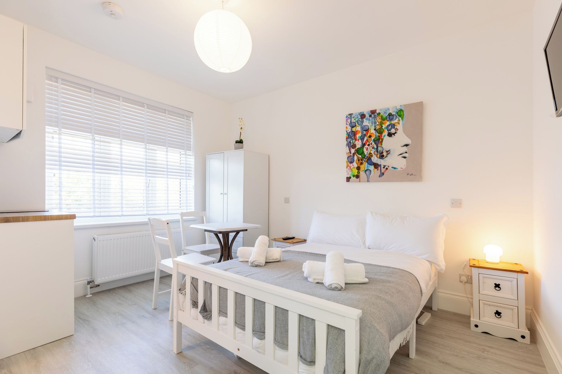 A modern bedroom with a bed, bedside table, and a painting on the wall.
