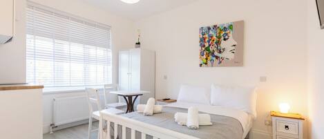A modern bedroom with a bed, bedside table, and a painting on the wall.