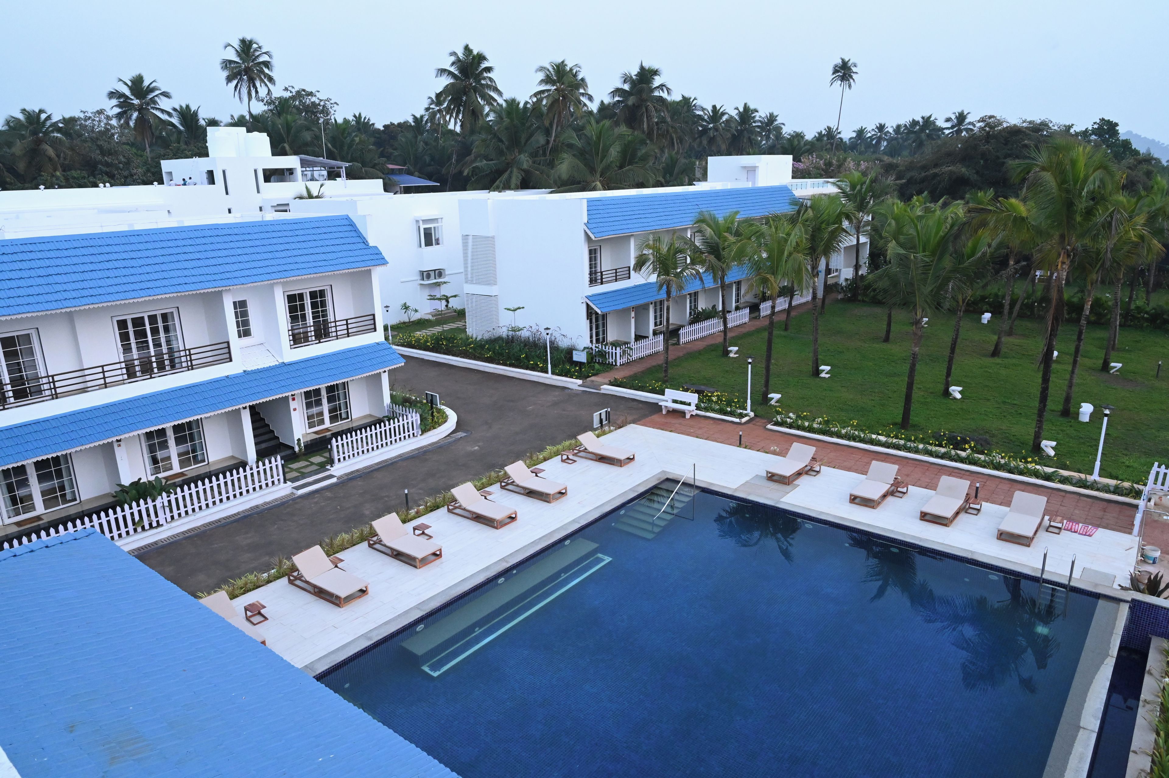 A hotel with a swimming pool, multiple balconies, and palm trees in the background.