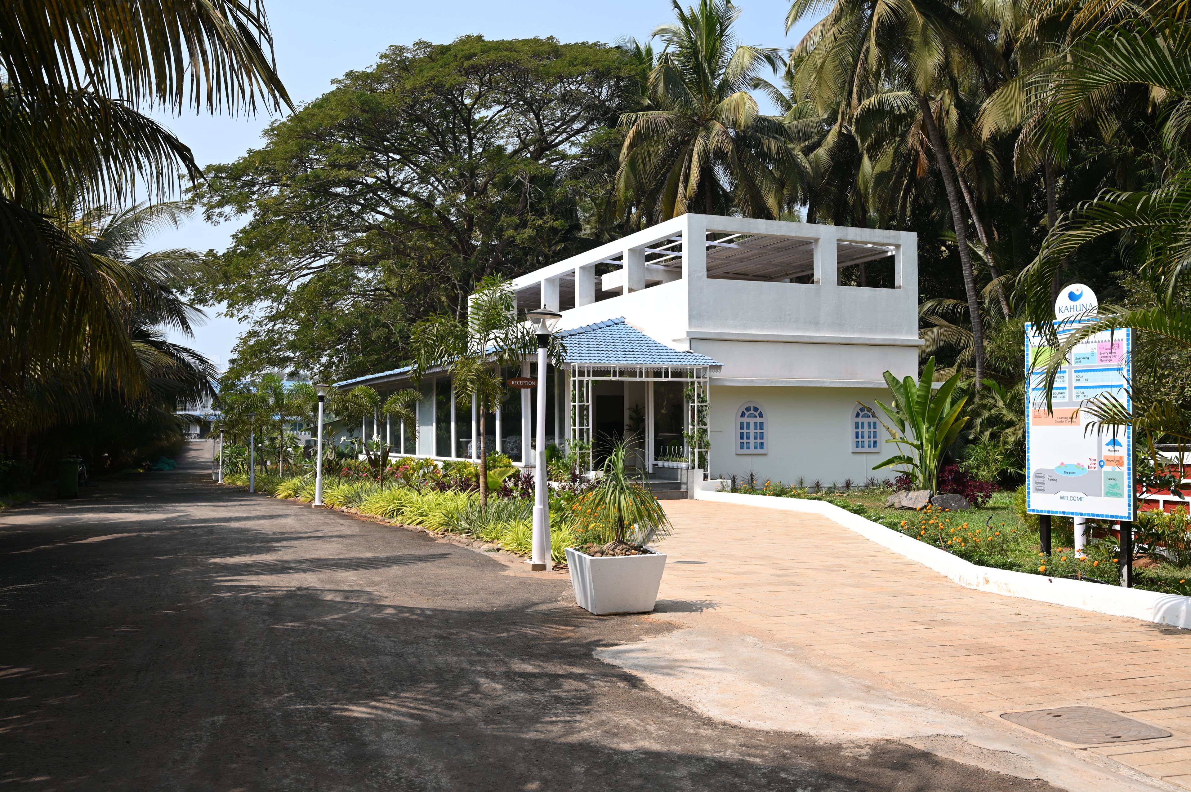 A two-story building with a reception area, surrounded by lush greenery and palm trees.