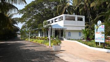 A two-story building with a reception area, surrounded by lush greenery and palm trees.