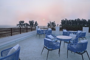 A terrace with blue wicker furniture and a view of the sea. - Kahuna Resorts - Find your Shore (Vengurla)