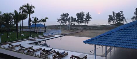 Zona junto a la piscina con tumbonas y vistas a la playa y al océano.