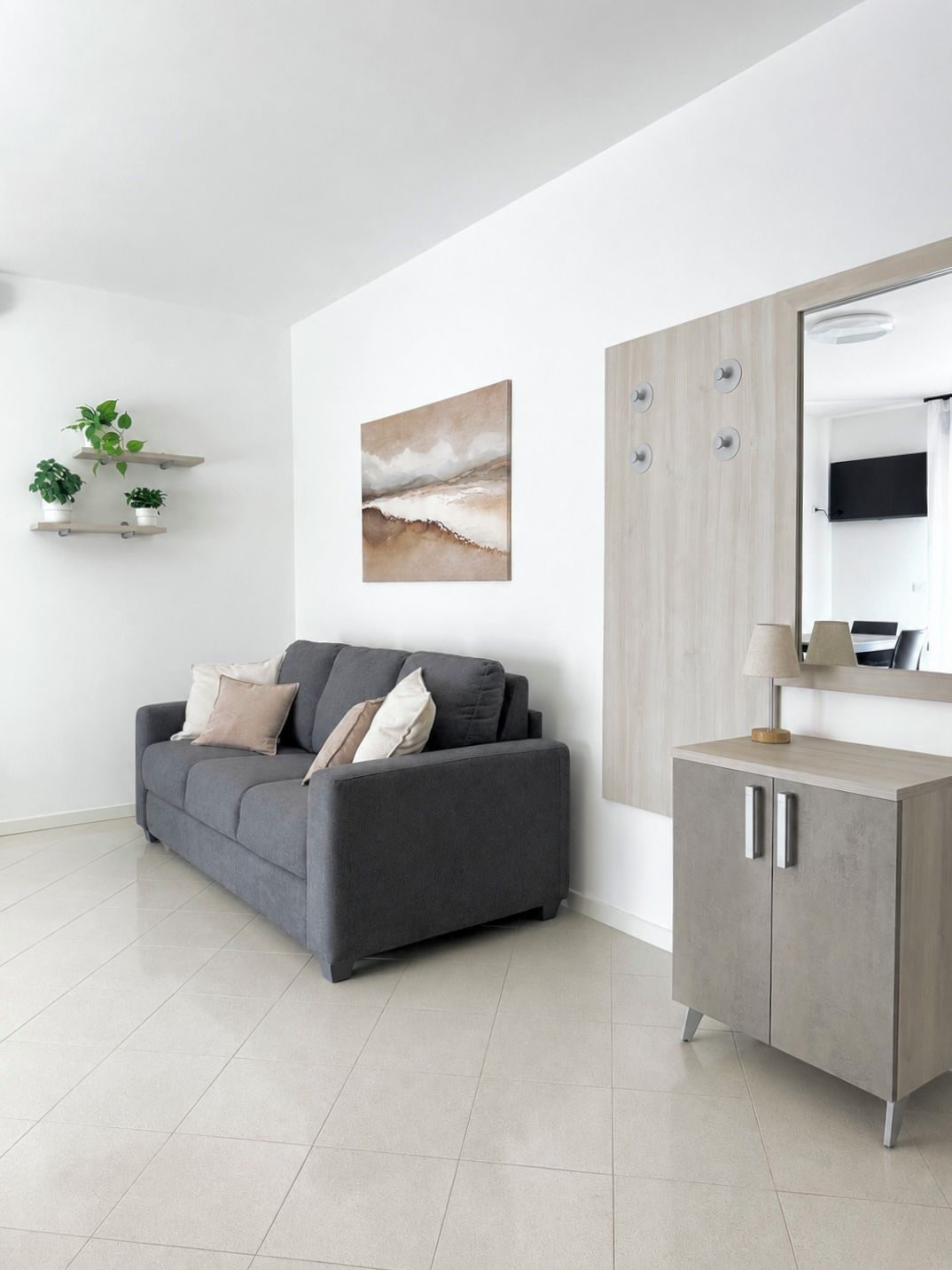 Un salon moderne avec un canapé gris, un meuble en bois et un tableau accroché au mur.