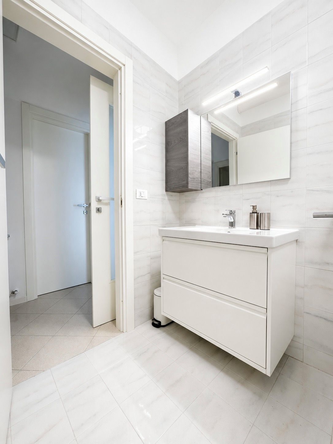 Een moderne badkamer met een wit wastafelmeubel, een spiegel en een toilet.
