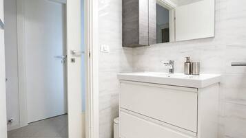 Een moderne badkamer met een wit wastafelmeubel, een spiegel en een toilet.