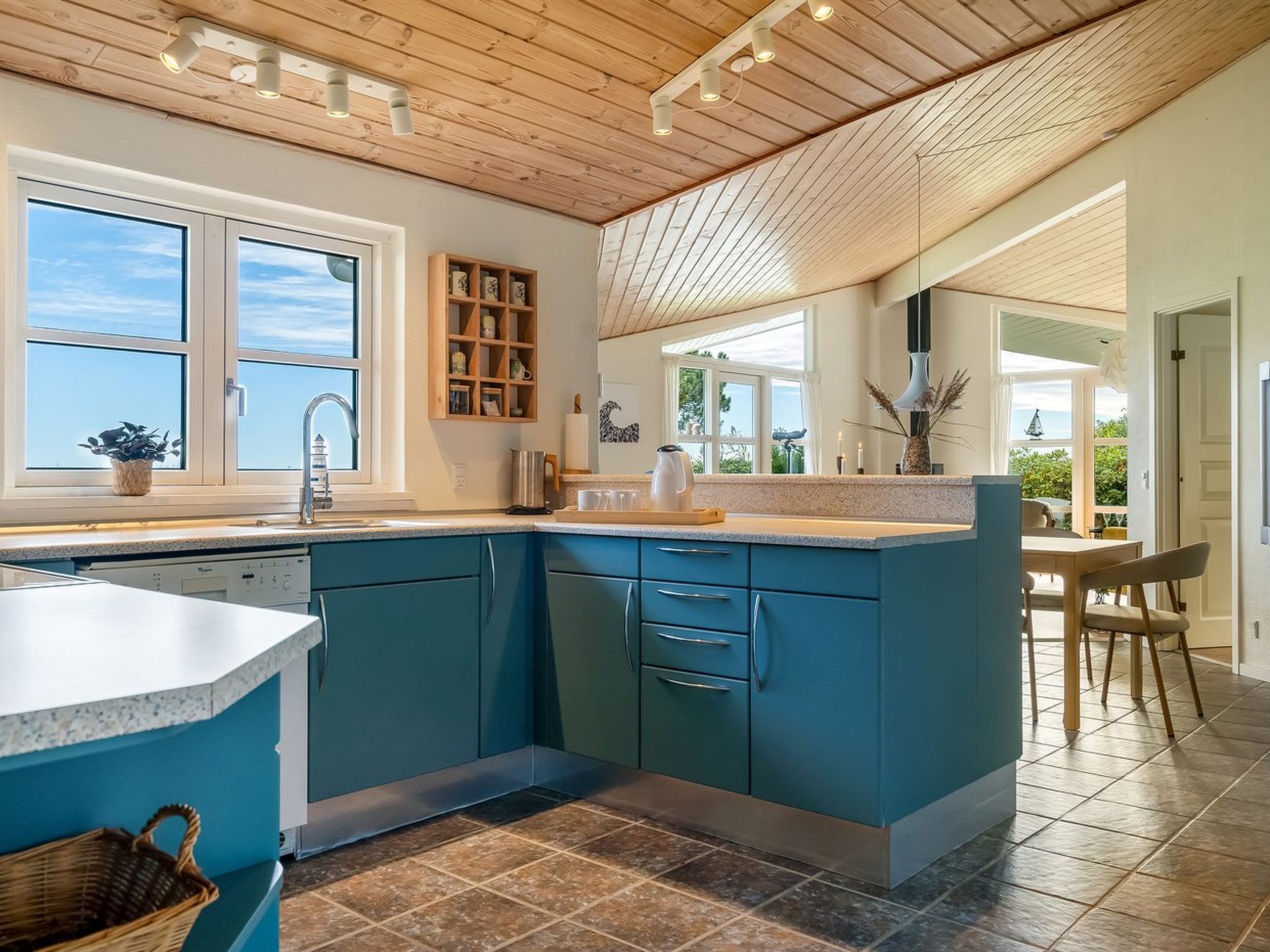 A modern kitchen with blue cabinets, a large island, and a view of the outdoors.