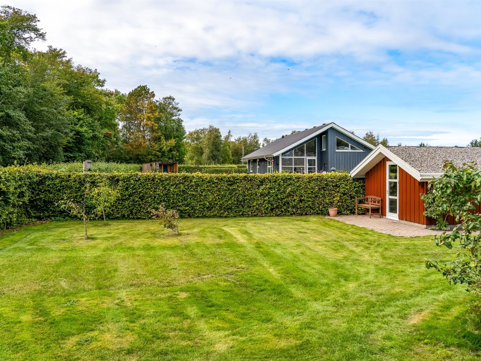 A modern house with a well-maintained lawn and a hedge.
