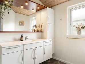A modern bathroom with white cabinetry, a wooden ceiling, and a window with a view. - "Heilo" -  from the sea by Interhome (Storvorde)