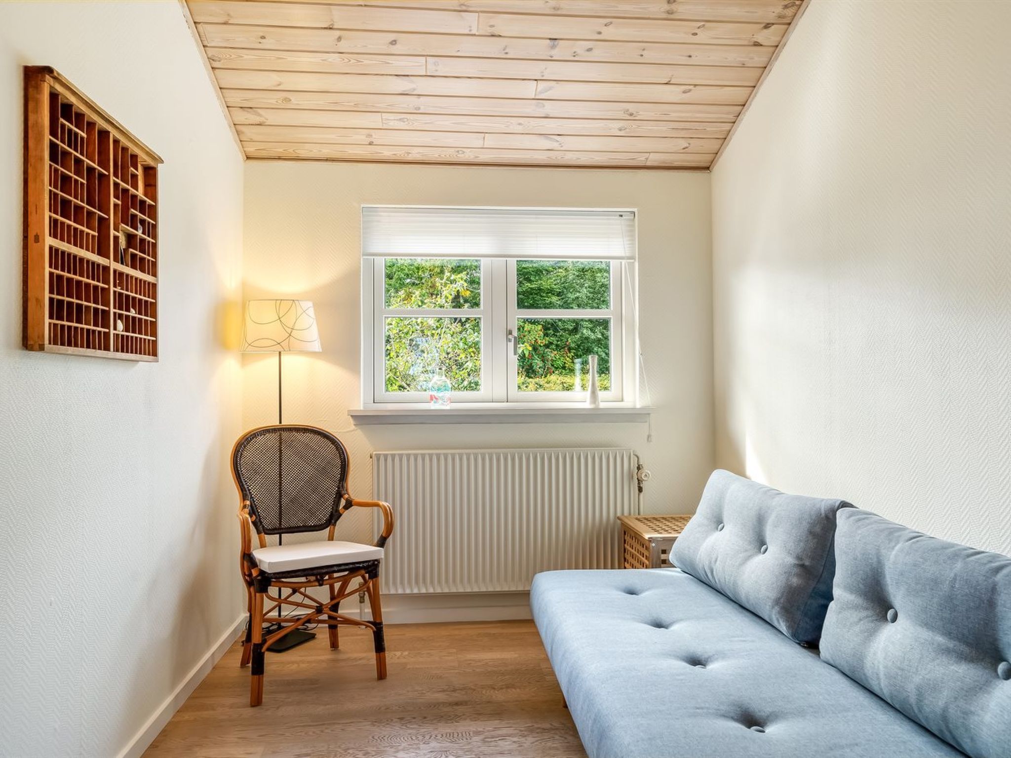 Een kamer met raam, radiator, stoel en bank.