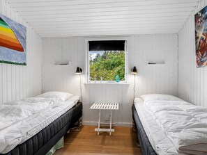 Een kamer met twee éénpersoonsbedden, een raam met uitzicht op groen en wandlampen.