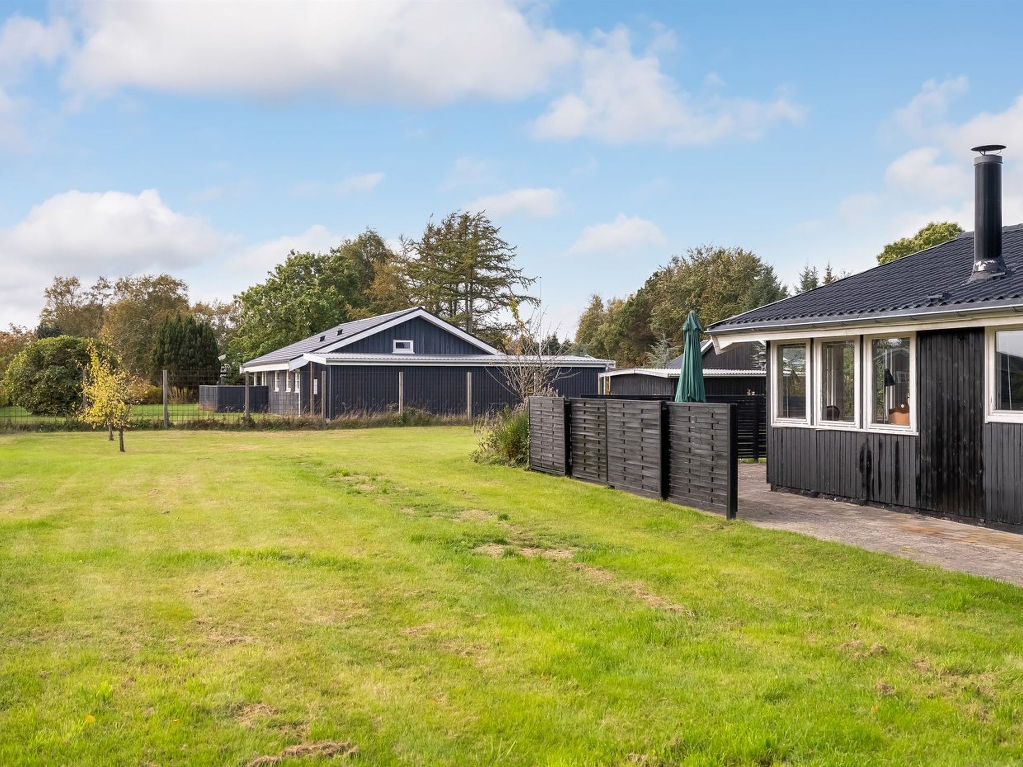 A residential property with a fenced yard, a detached garage, and a house with a sloped roof.