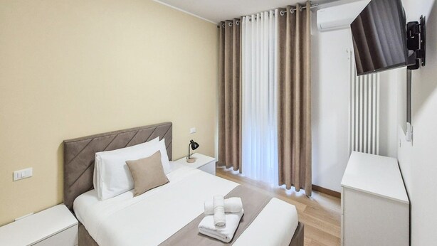 Une chambre d’hôtel équipée d’un lit, d’une table de chevet, d’une lampe et d’un téléviseur fixé au mur.
