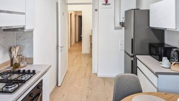 Una cocina moderna con estufa a gas, refrigerador y microondas.