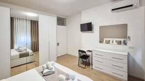 Een hotelkamer met een bed, een bureau, een stoel, een kledingkast en een airco.