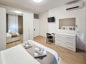 A hotel room with a bed, a desk, a chair, a wardrobe, and an air conditioning unit. - defaultName (Vicenza)