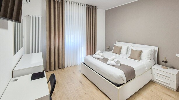 Een moderne hotelkamer met een bed, nachtkastje en een bureau met stoel.