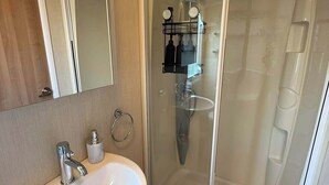 A bathroom with a white sink, a glass shower enclosure, and a mirror.