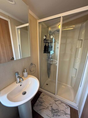 A bathroom with a white sink, a glass shower enclosure, and a mirror.