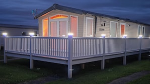 A mobile home with a fenced deck and multiple windows.