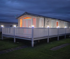 A mobile home with a fenced deck and multiple windows.