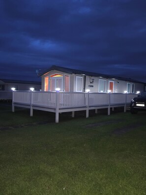 Ein Bungalow mit einem eingezäunten Deck, einer überdachten Veranda und einer Garage.
