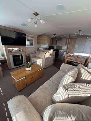 Un espacio habitable funcional con sofá, mesa de centro, televisor de pantalla plana y cocina equipada con estufa y microondas.