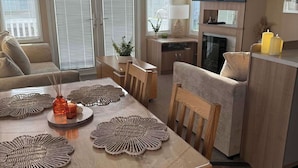 A modern living room with a dining table, sofa, and kitchen area.