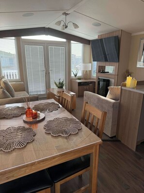 A modern living room with a dining table, sofa, and kitchen area.