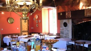 A dining area with tables set for breakfast, a chandelier, and a fireplace. - Château D'Island: Delphine Suite (Island)