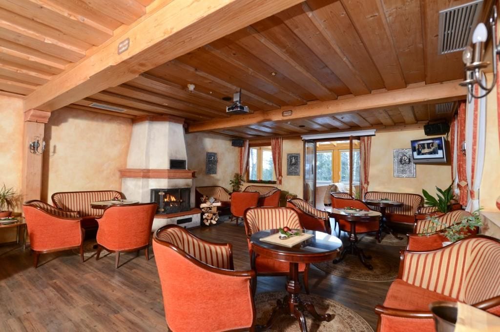 Un salón con suelo de madera, sillas a rayas, chimenea y zona de comedor.