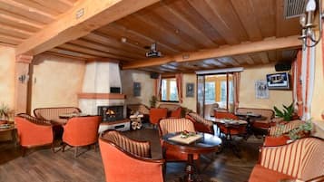 Un salón con suelo de madera, sillas a rayas, chimenea y zona de comedor.