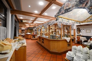 L’intérieur d’un restaurant est aménagé avec des meubles en bois, un sol carrelé et un espace central dédié au service.