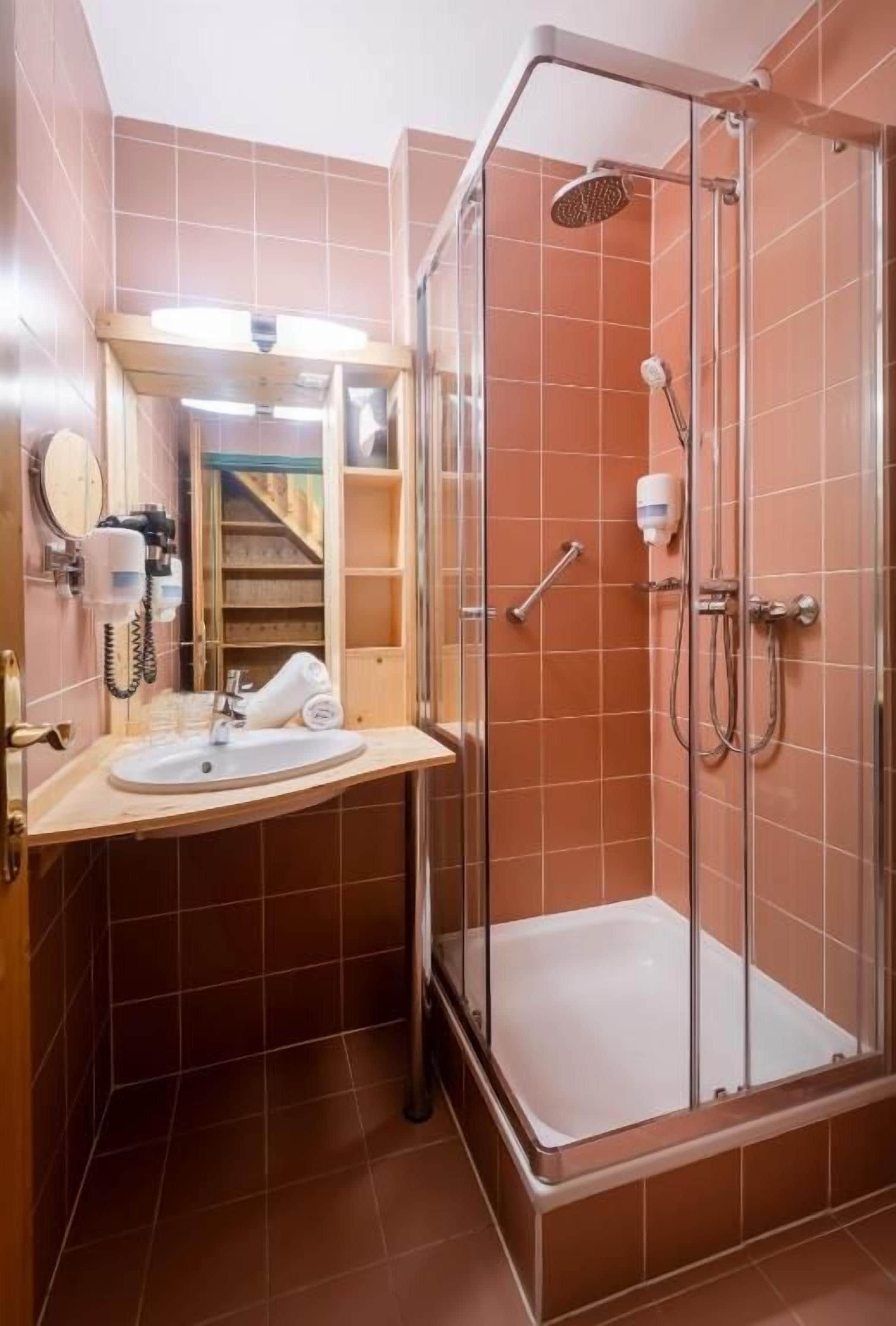 Ein Badezimmer mit einer Duschkabine, einem Waschbecken und einem Spiegel.