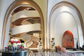 A modern lobby with a spiral staircase, seating area, and a reception desk.