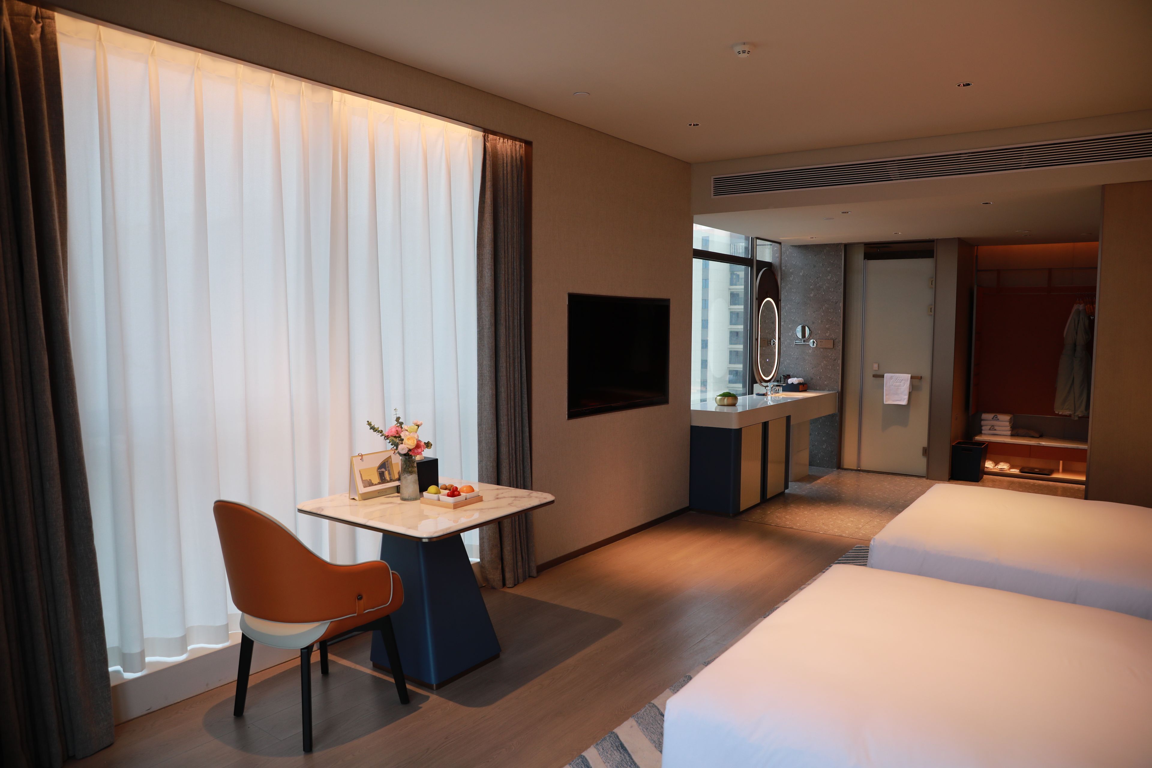 Une chambre d’hôtel comprenant un lit, un bureau avec une chaise, une télévision et une salle de bain avec un miroir et un lavabo.