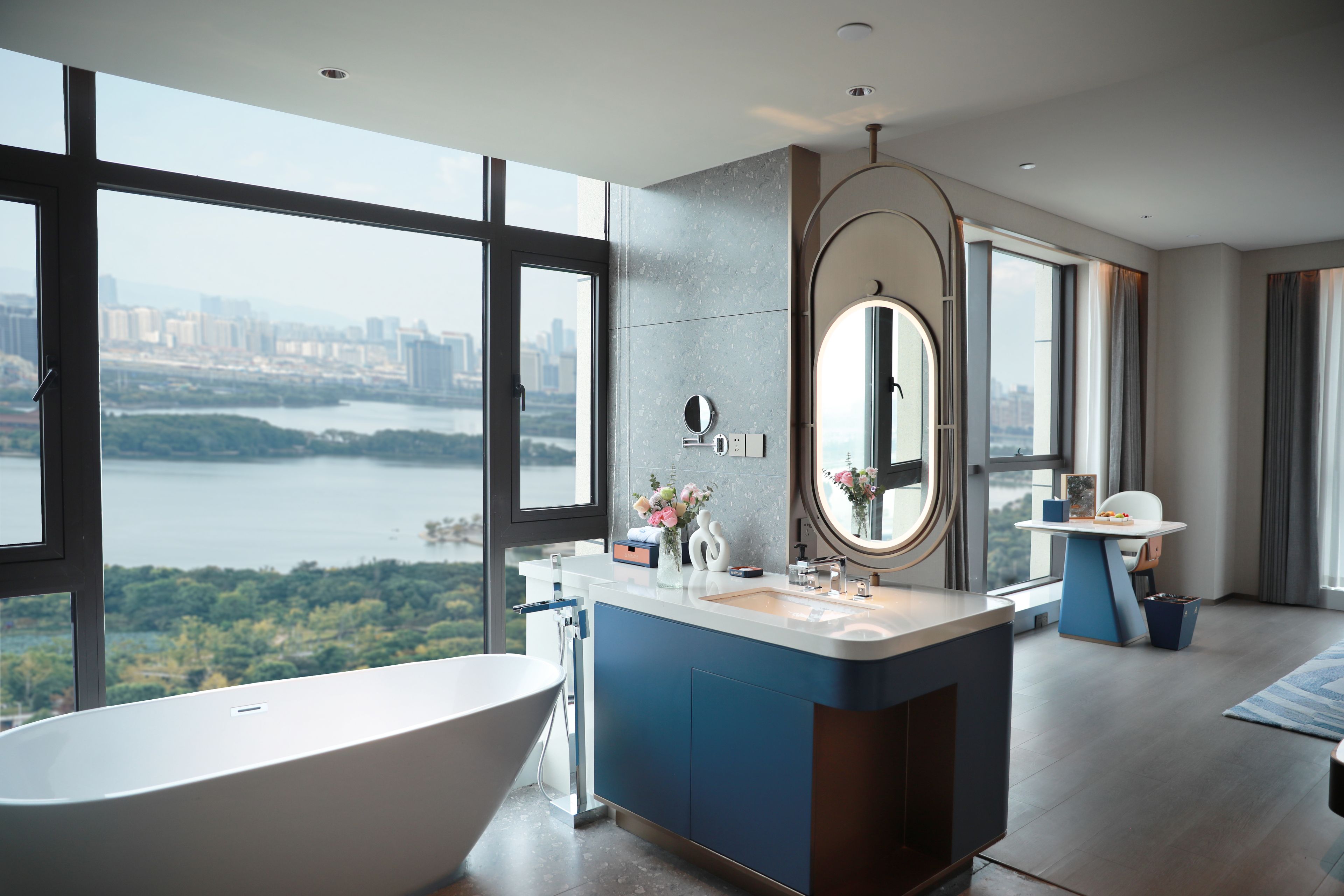 Un baño moderno con una bañera independiente, un espejo grande y un tocador con lavabo.