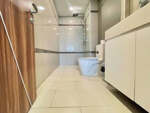A modern bathroom with a toilet, shower, and vanity. - Room-top Floor Duplex With High Ceiling (Pattaya)