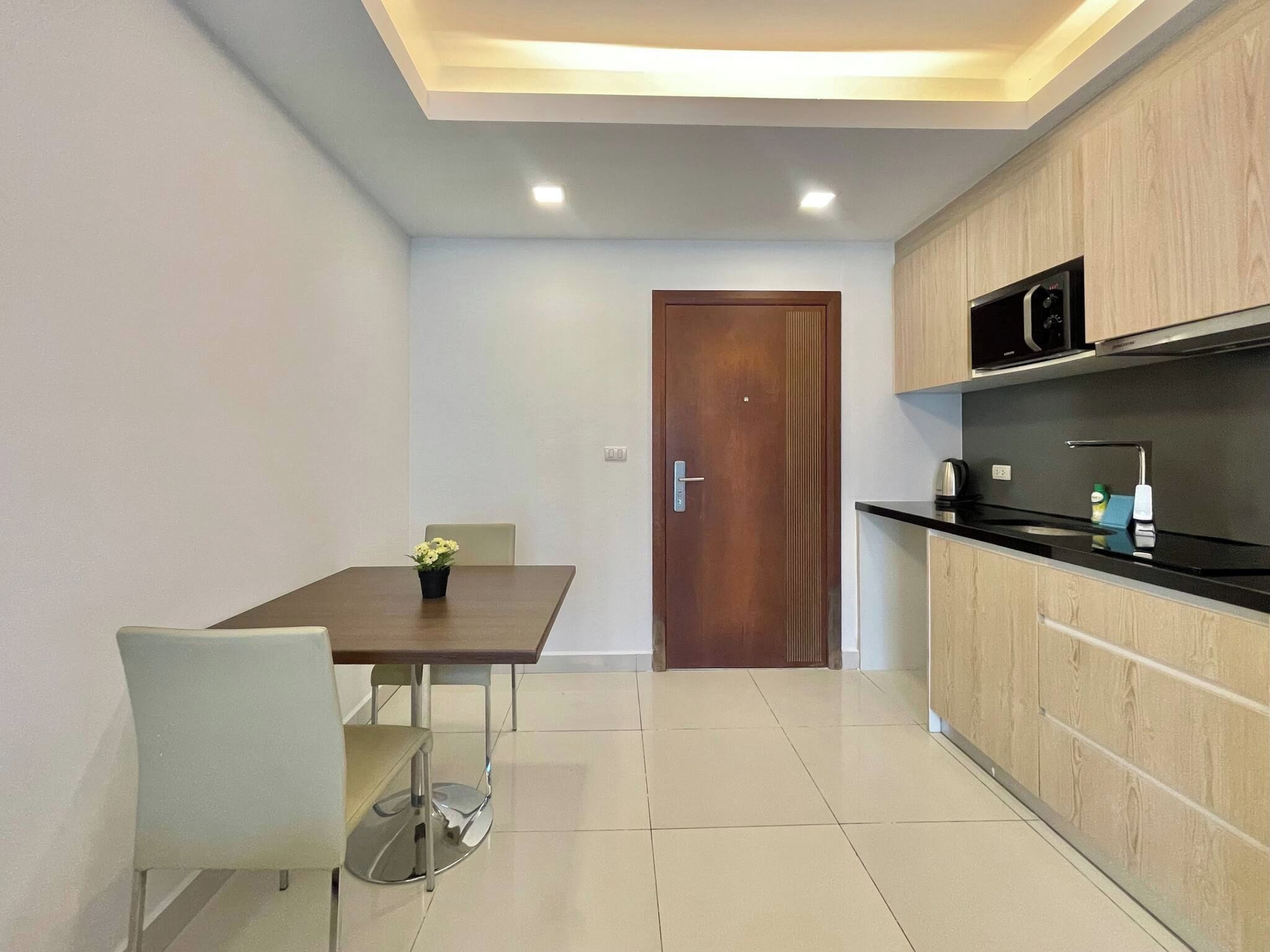 Una cocina moderna con una puerta de madera, una mesa de comedor con una silla y una pequeña planta en maceta.