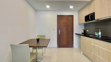 Una cocina moderna con una puerta de madera, una mesa de comedor con una silla y una pequeña planta en maceta.