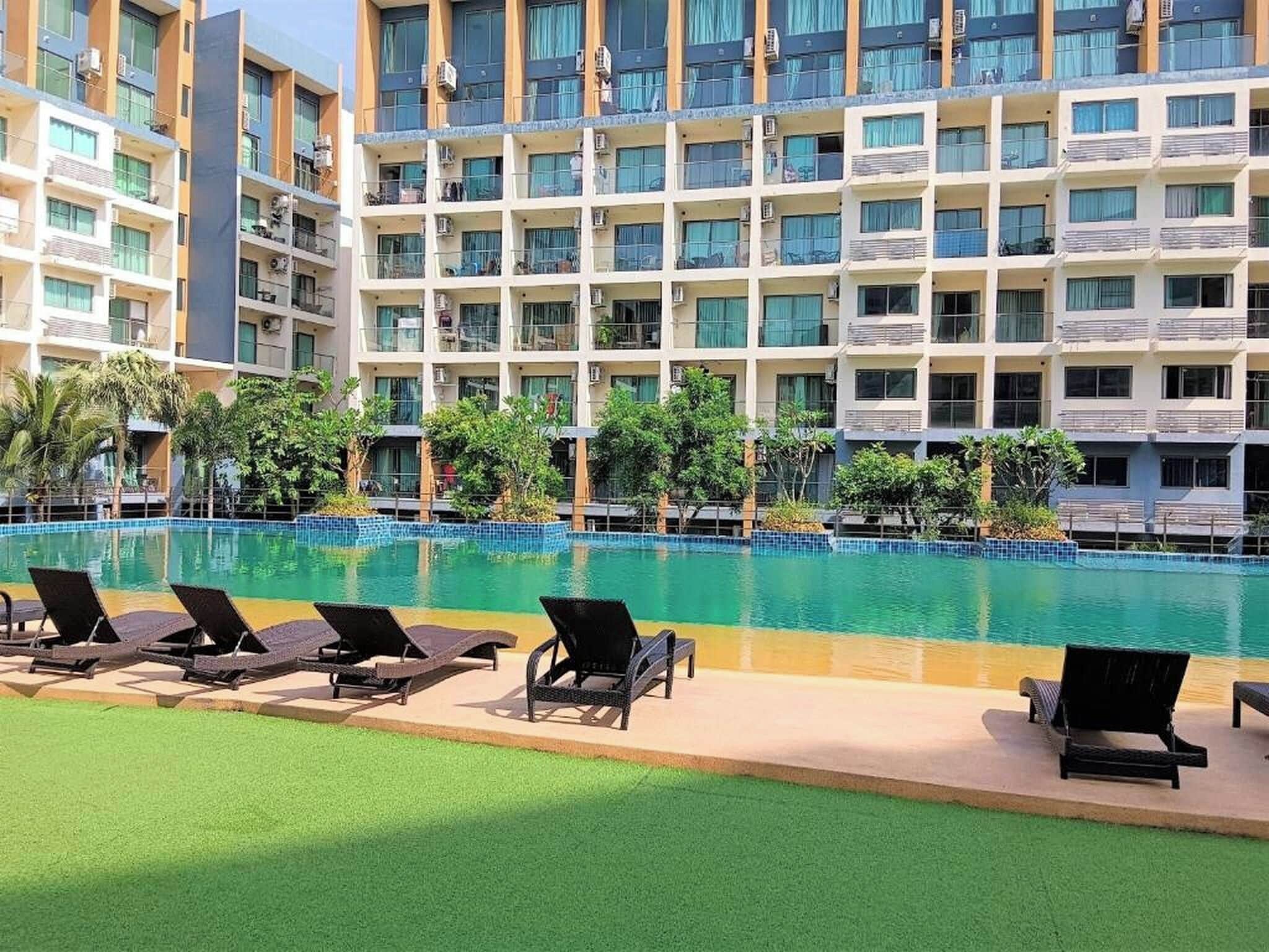 A hotel with a swimming pool, multiple balconies, and outdoor seating.