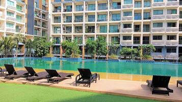 Un hôtel doté d’une piscine, de plusieurs balcons et d’un espace extérieur aménagé pour s’asseoir.
