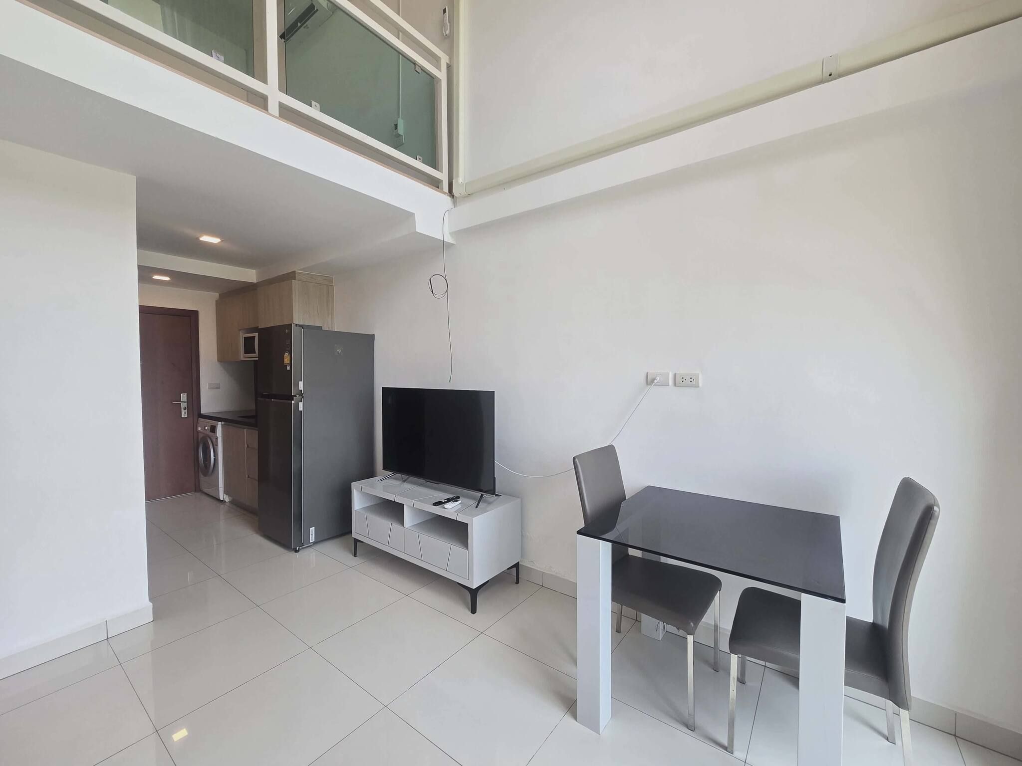 A modern kitchen with a refrigerator, microwave, and a dining area with a table and chairs.