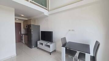 A modern kitchen with a refrigerator, microwave, and a dining area with a table and chairs.